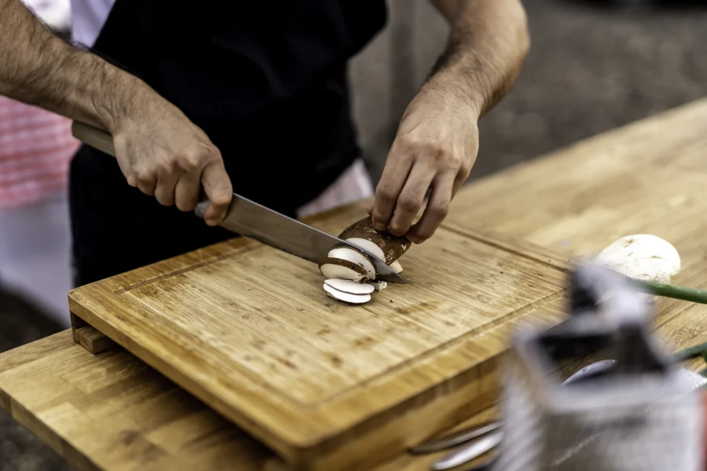 Cook slicing onions with a chef knife on a cutting board