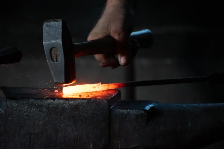 Blacksmith hammering a red-hot steel bar on an anvil